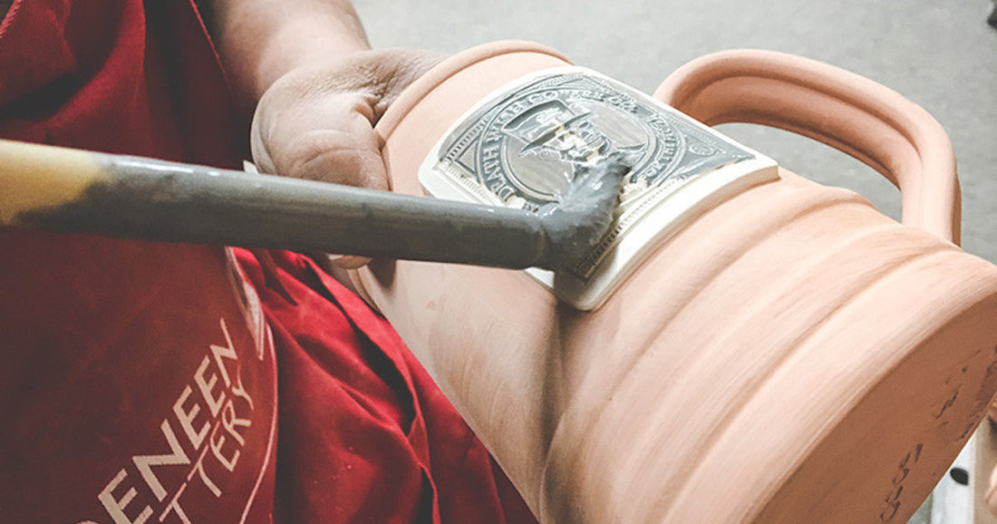 Brushing the glaze onto a handcrafted mug made by Deneen Pottery.