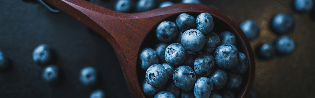 Blueberries inside of a wooden scoop.