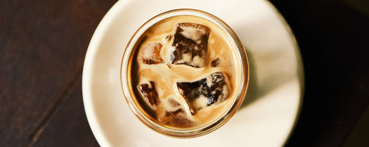 An aerial shot of a mason jar on a small white plate with iced coffee.