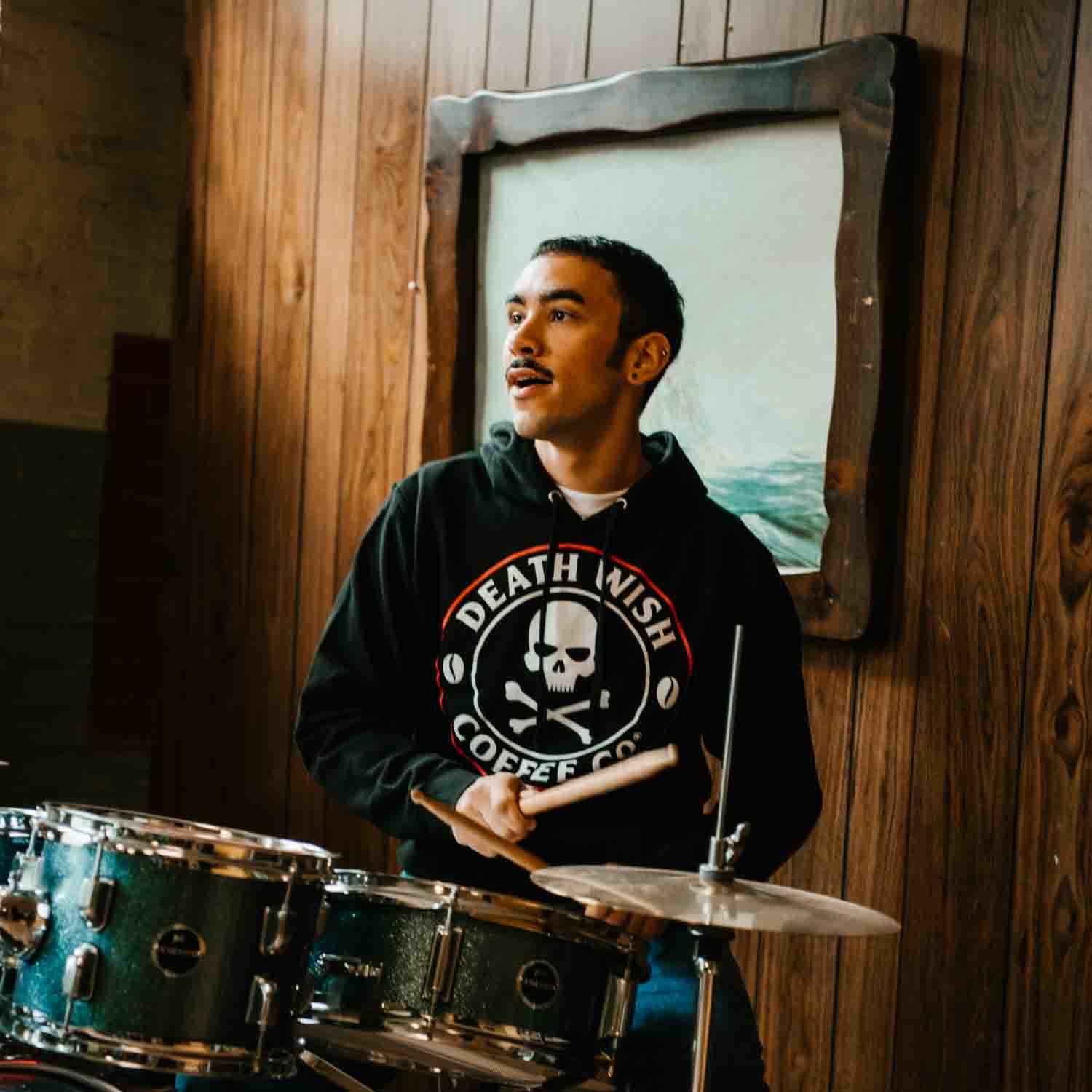 Playing the drums in the Death Wish Coffee Classic Logo Hoodie.