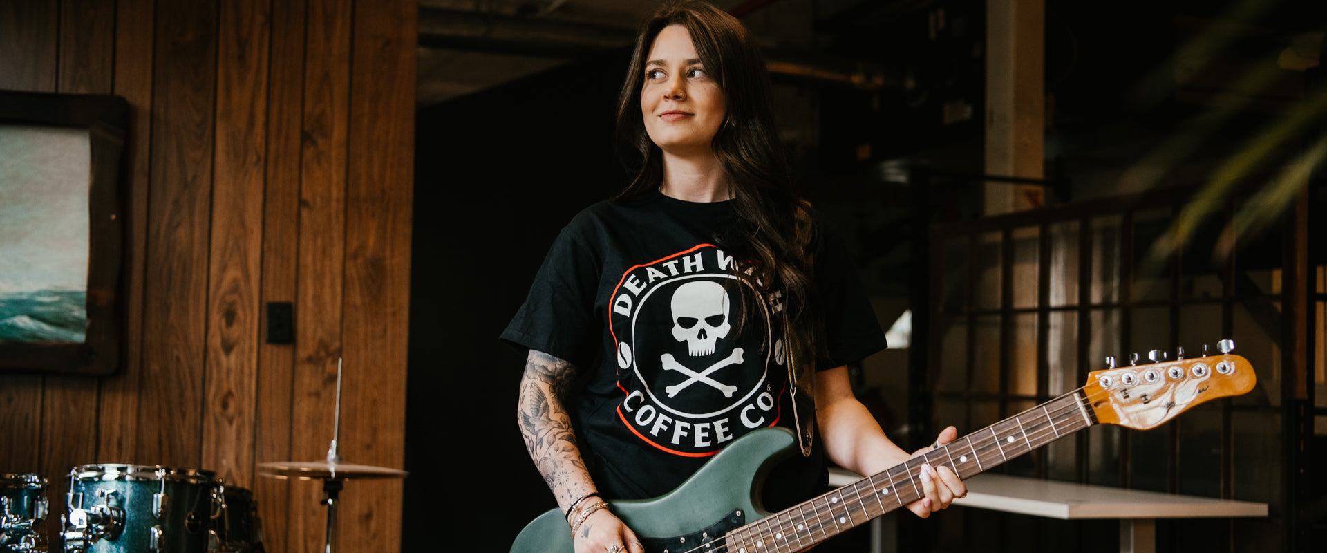 A girl playing guitar in the Death Wish Coffee Core Classic Logo Tee.