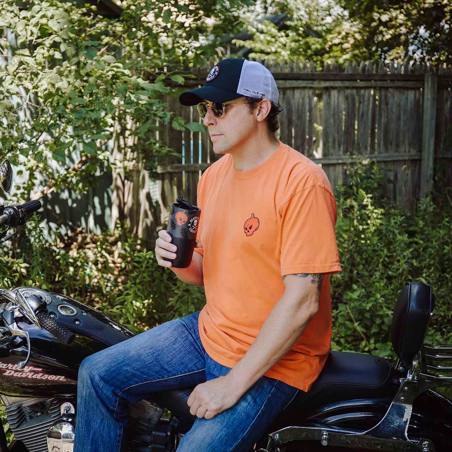 A model wearing the Death Wish Coffee Pumpkin To Talk About Tee and drinking from the matching Klean Kanteen.