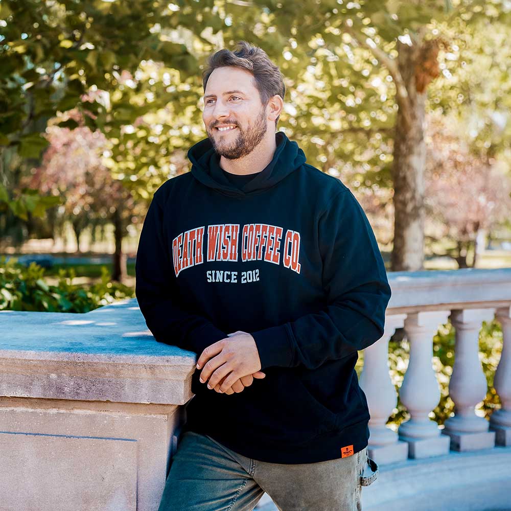 A model wearing the Death Wish Coffee Varsity Brews Hoodie.