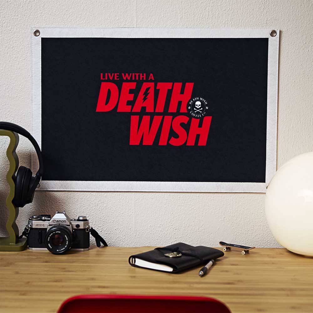 The Death Wish Coffee Doctrine Banner hanging on the wall above a desk.