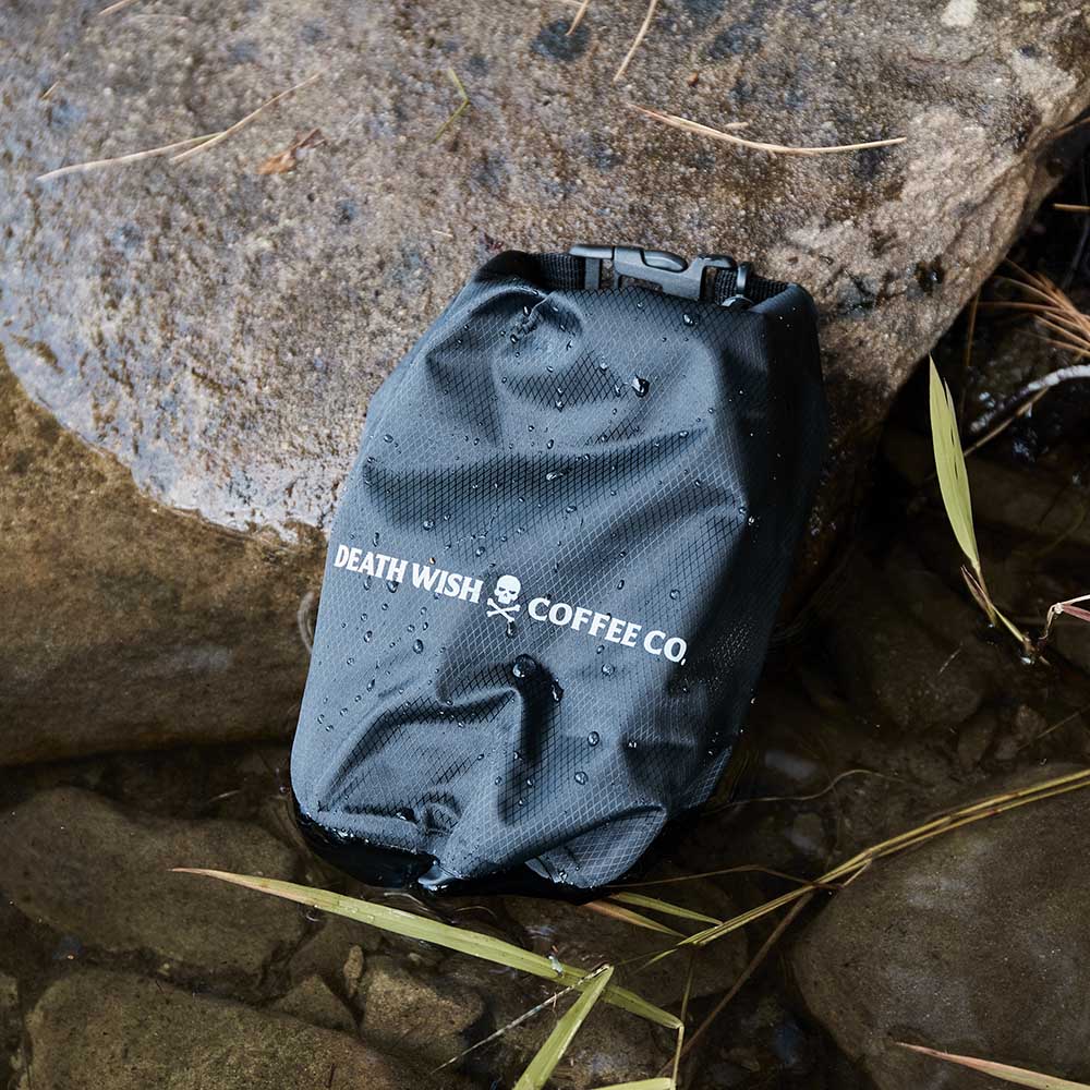 The Death Wish Coffee Rock The Boat Waterproof Bag resting on a rock.