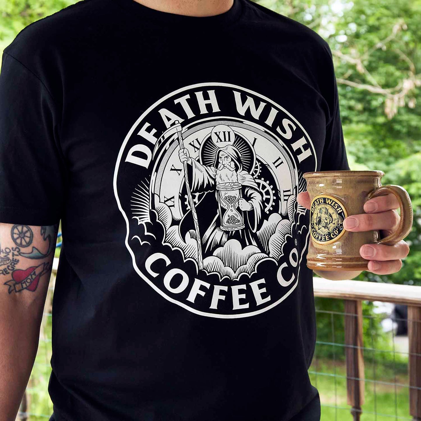 A model wearing the Death Wish Coffee Father Time Tee and using the matching Father Time Mug.