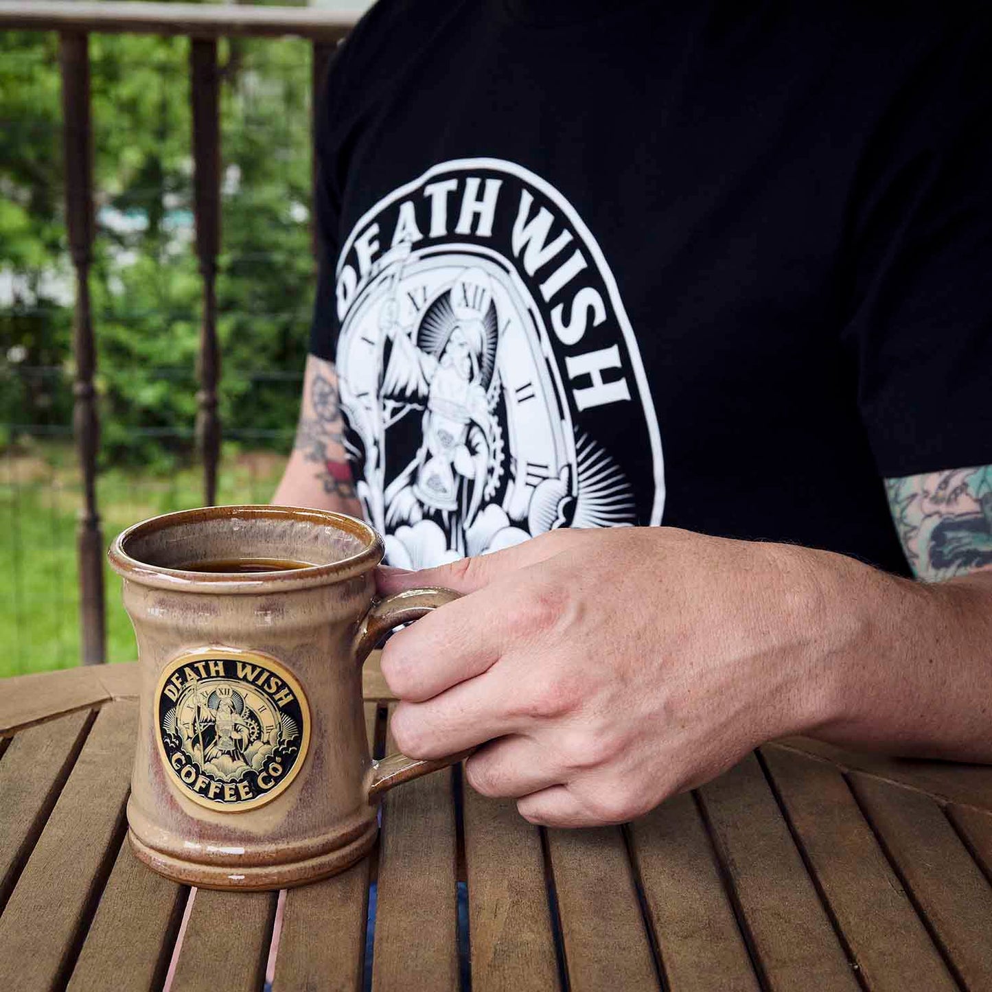 A model wearing the Death Wish Coffee Father Time Tee and using the matching Father Time Mug.