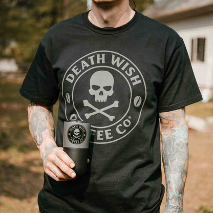 A man holding a cup of coffee and wearing the Death Wish Coffee Shadow Logo Tee.