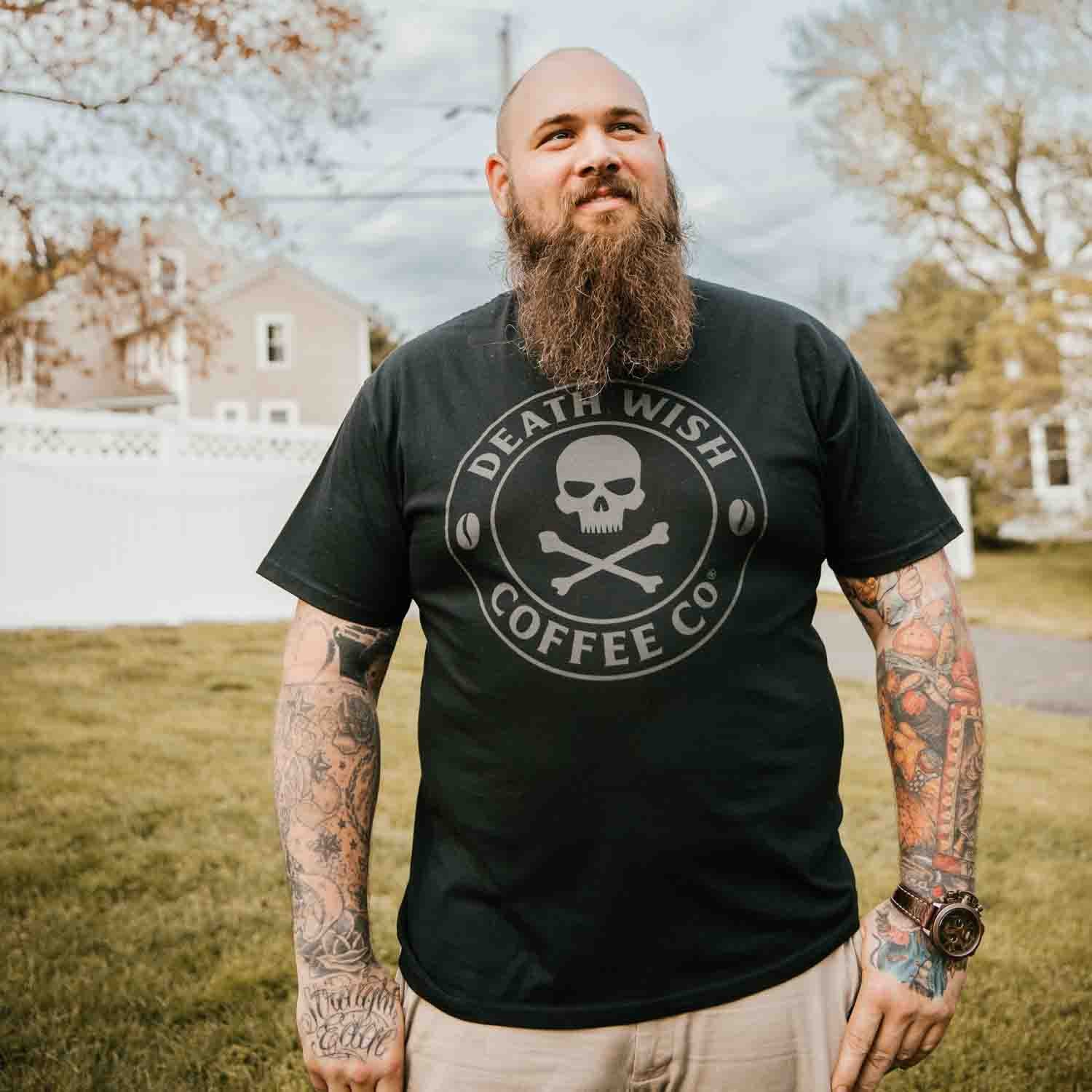 A man with tattoos wearing the Death Wish Coffee Shadow Logo Tee.