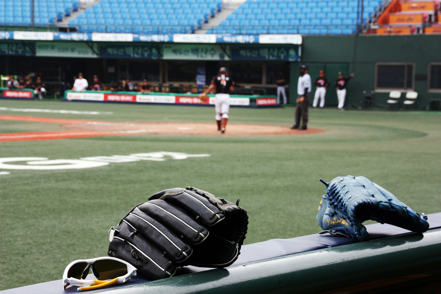 Baseball gloves sitting on the edge of a dugout during a game.
