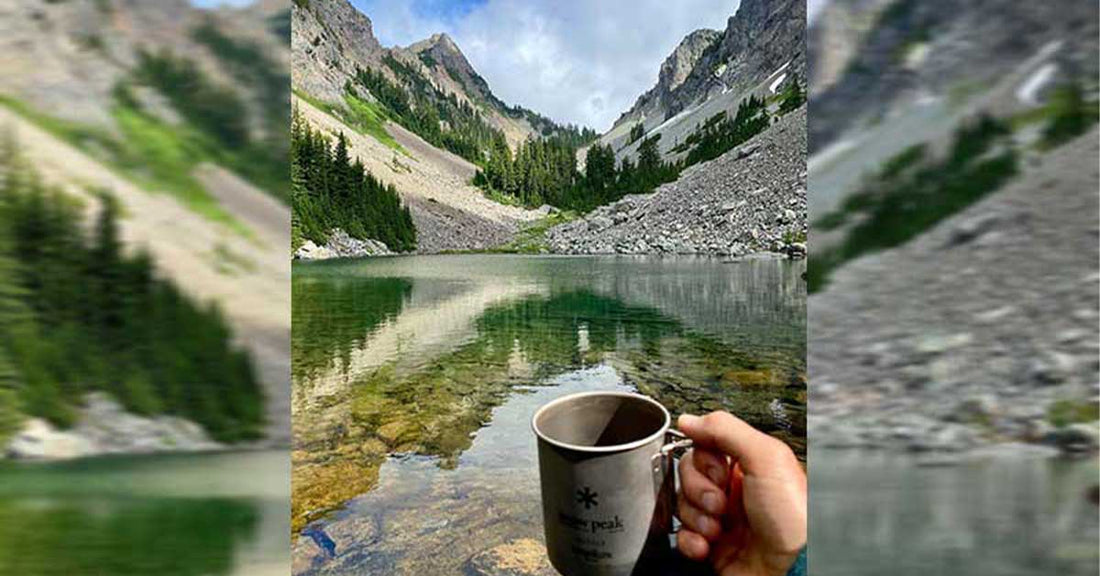 Valley in North Bend, Oregon, with a hand holding a cup of coffee in the foreground