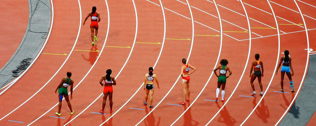 A track filled with a lineup of female runners at the starting line.