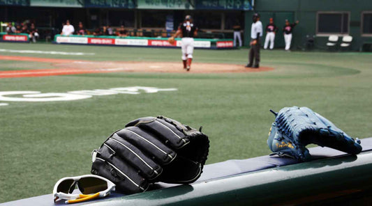 Two baseball gloves sitting in a dugout at a baseball game