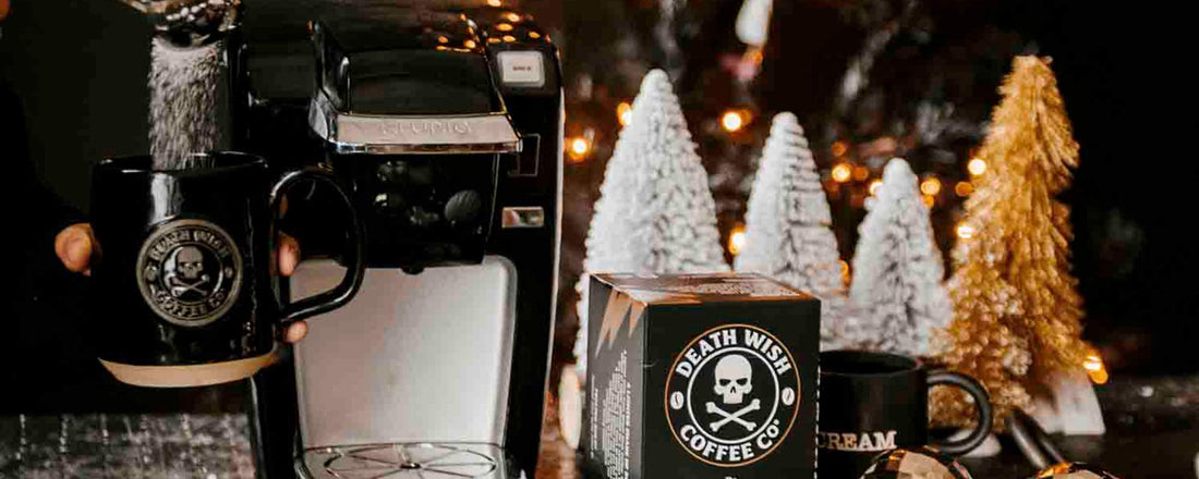 A table covered in holiday decorations and a coffee maker, mug and coffee pods. 