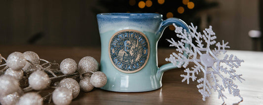 A Jack Frost Coffee Mug on a coffee table next to a snowflake ornament and holiday decorations.