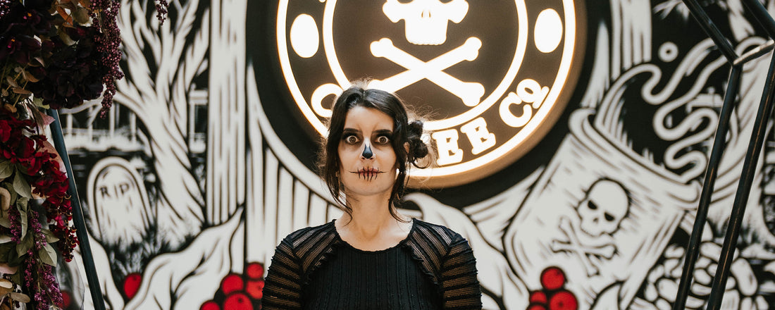 A female with demonic face painting standing in front of a Death Wish mural.