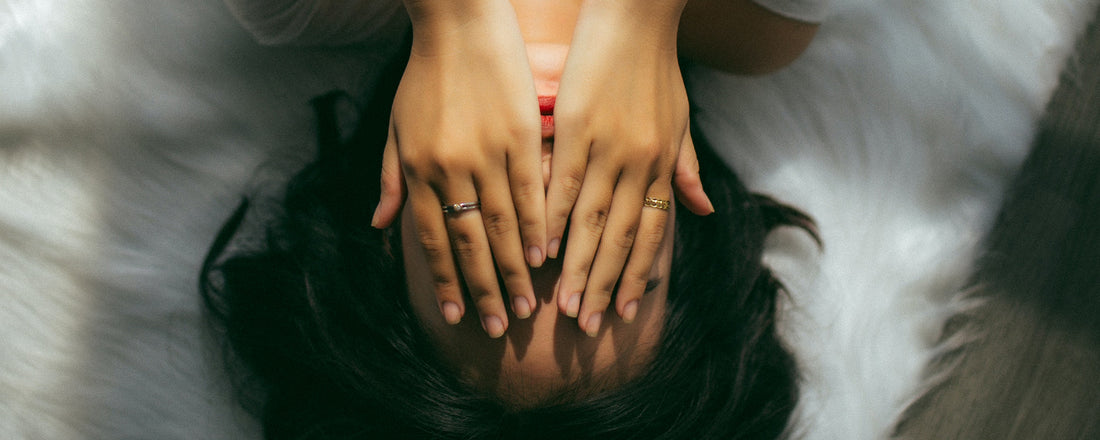 A woman laying with her hands over her head. Photo Credit: Anthony Tran via Unsplash.