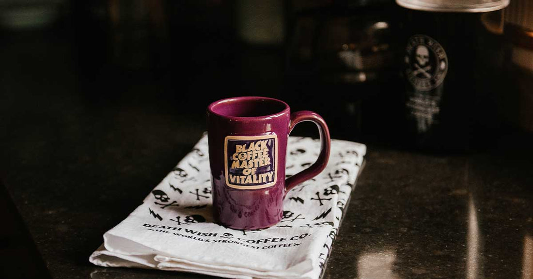 Mug that reads "Black Coffee Master of Vitality" sitting on top of a Death Wish Coffee towel