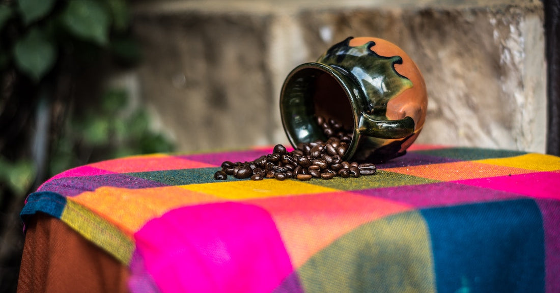 Brown and black ceramic coffee mug pouring out coffee beans