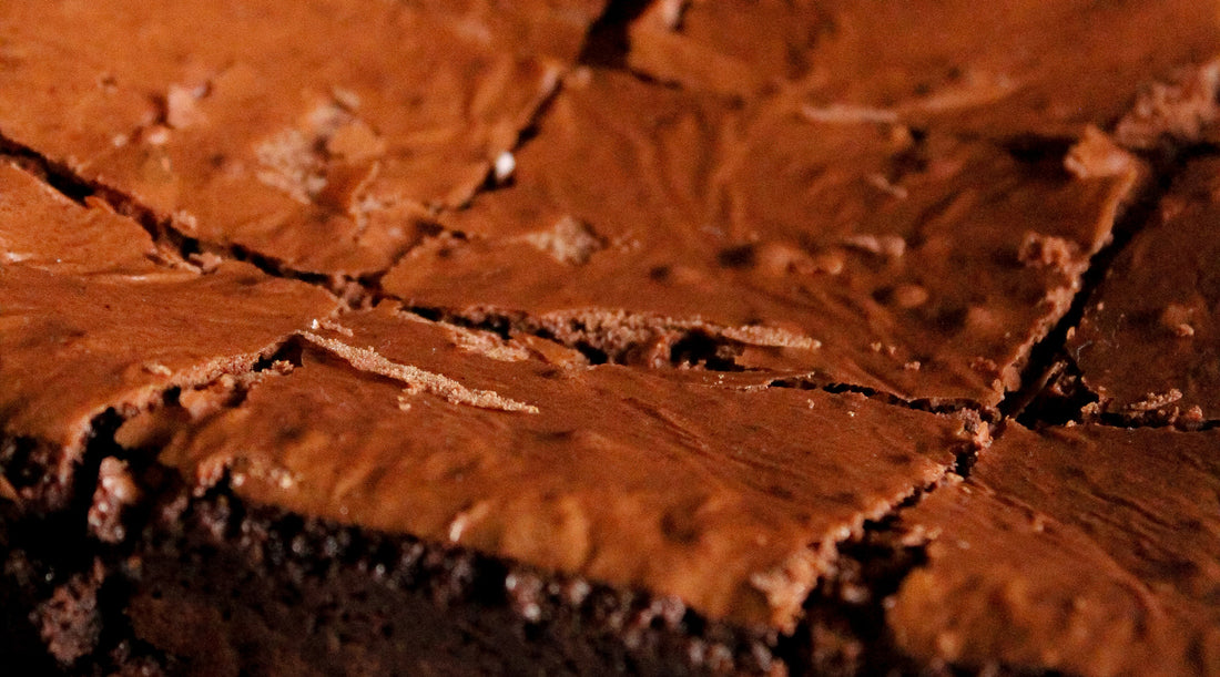A close up image of freshly baked brownies with a flaky crust.