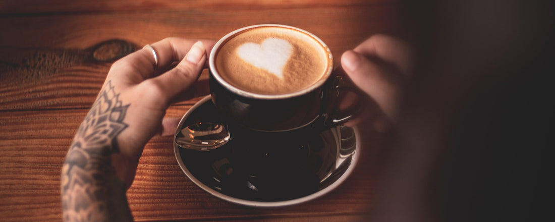 An image of a woman holding a latte with a heart crafted in the foam. Photo Credit: Byron Breytenbach