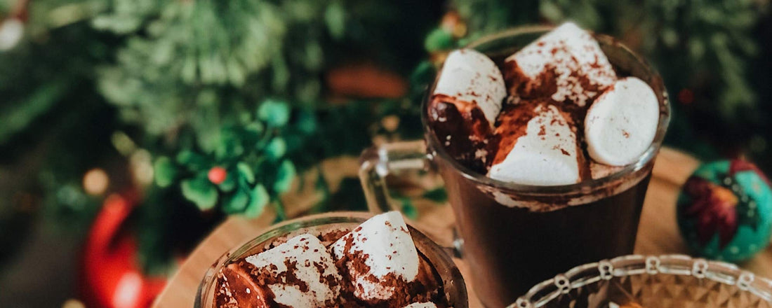 Two coffee cocktails with marshmallows and chocolate syrup on top. 