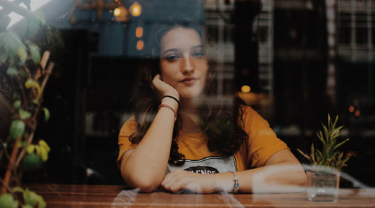 A woman looking out the window of a coffee shop.