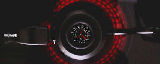 An aerial shot of a gooseneck stovetop kettle sitting on a black stovetop with a red burner.
