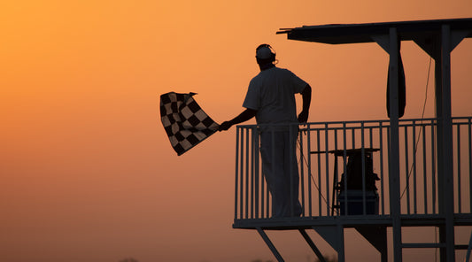 A silhouette of a man waving a checkered flag.