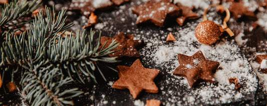 Pine needles one a black countertop with flower and gingerbread scattered on top.