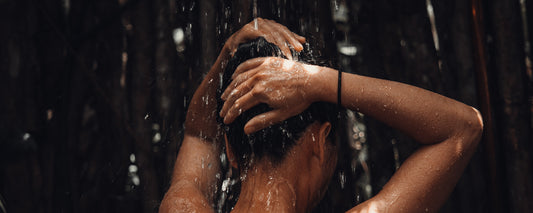 A woman taking a shower with her hands on her head. Photo Credit: Robert Gomez via Unsplash.