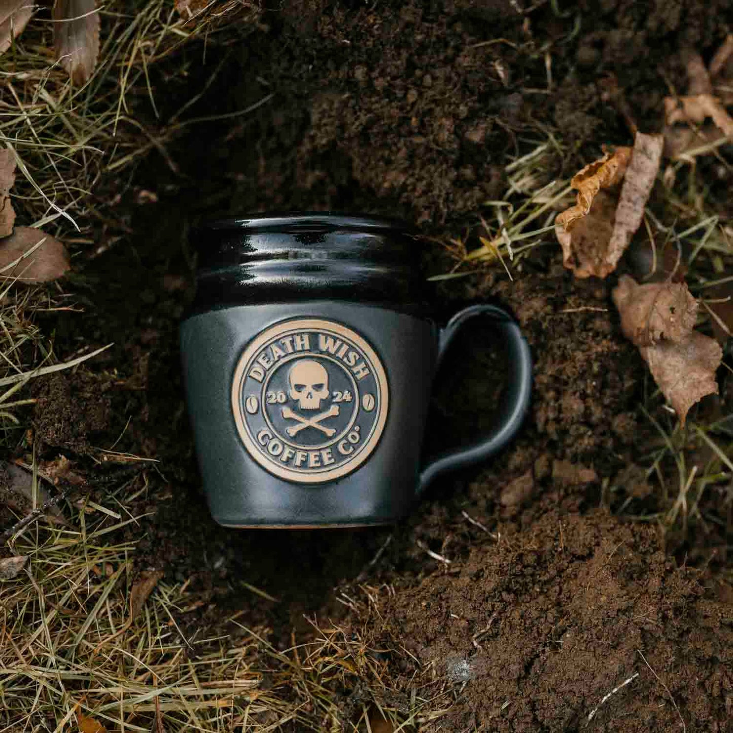 The 2024 Death Wish Coffee Mug buried in the dirt.