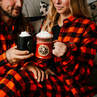 A couple doing a cheers with their mugs in the Death Wish Coffee Flannel Pants.