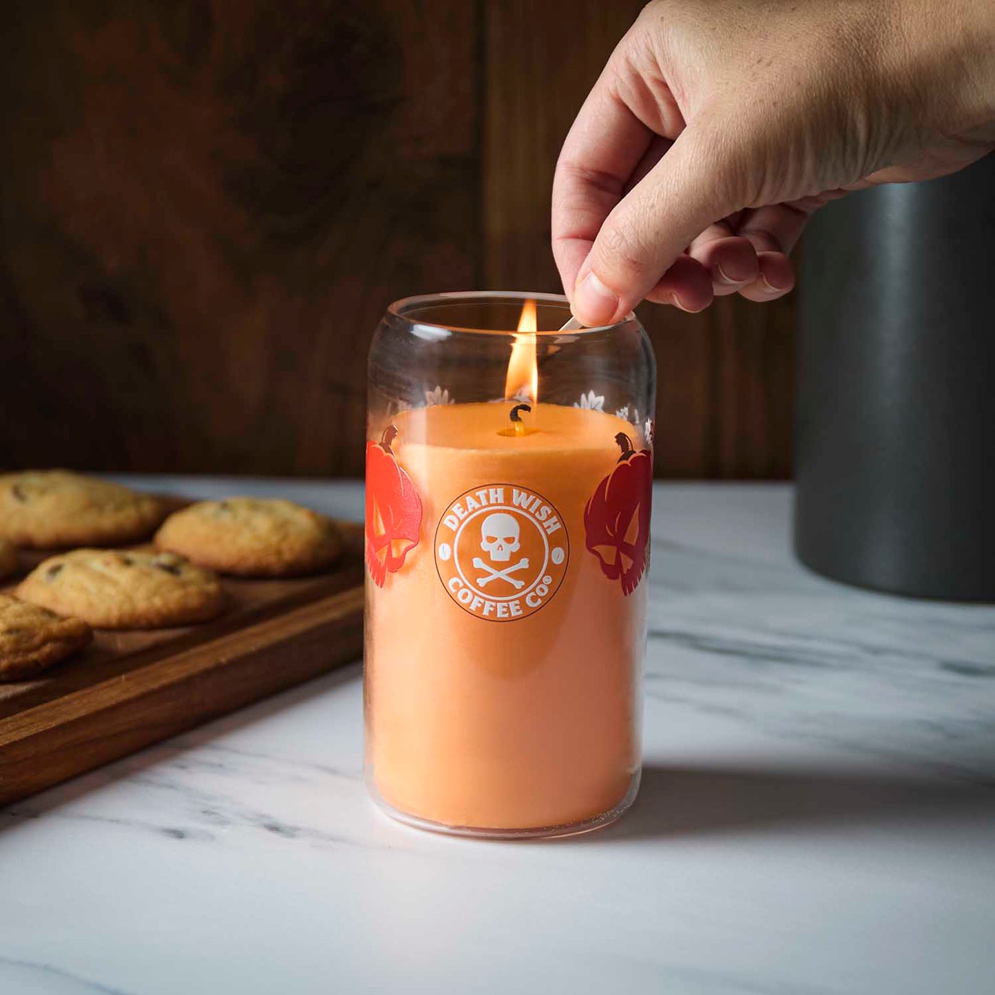 A hand lighting the Death Wish Coffee Pumpkin Chai Soda Can Candle.