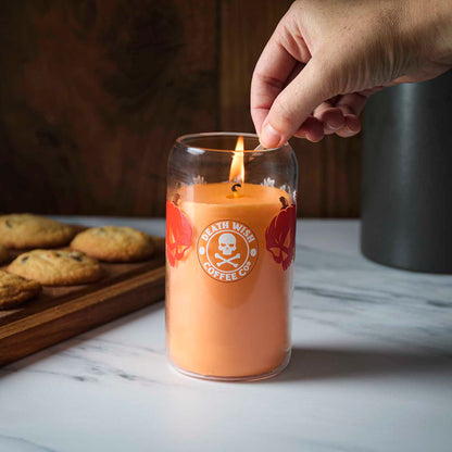 A hand lighting the Death Wish Coffee Pumpkin Chai Soda Can Candle.