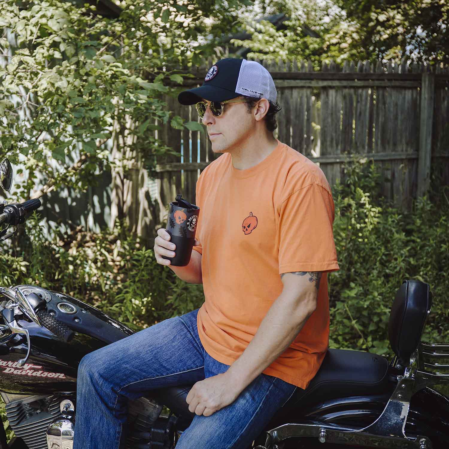 A model wearing the Death Wish Coffee Pumpkin To Talk About Tee and drinking from the matching Klean Kanteen.