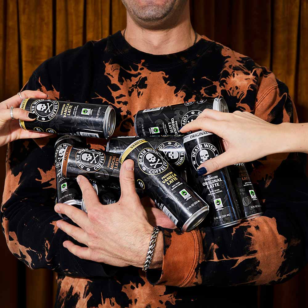 A model holding a hand full of Death Wish Coffee latte cans.