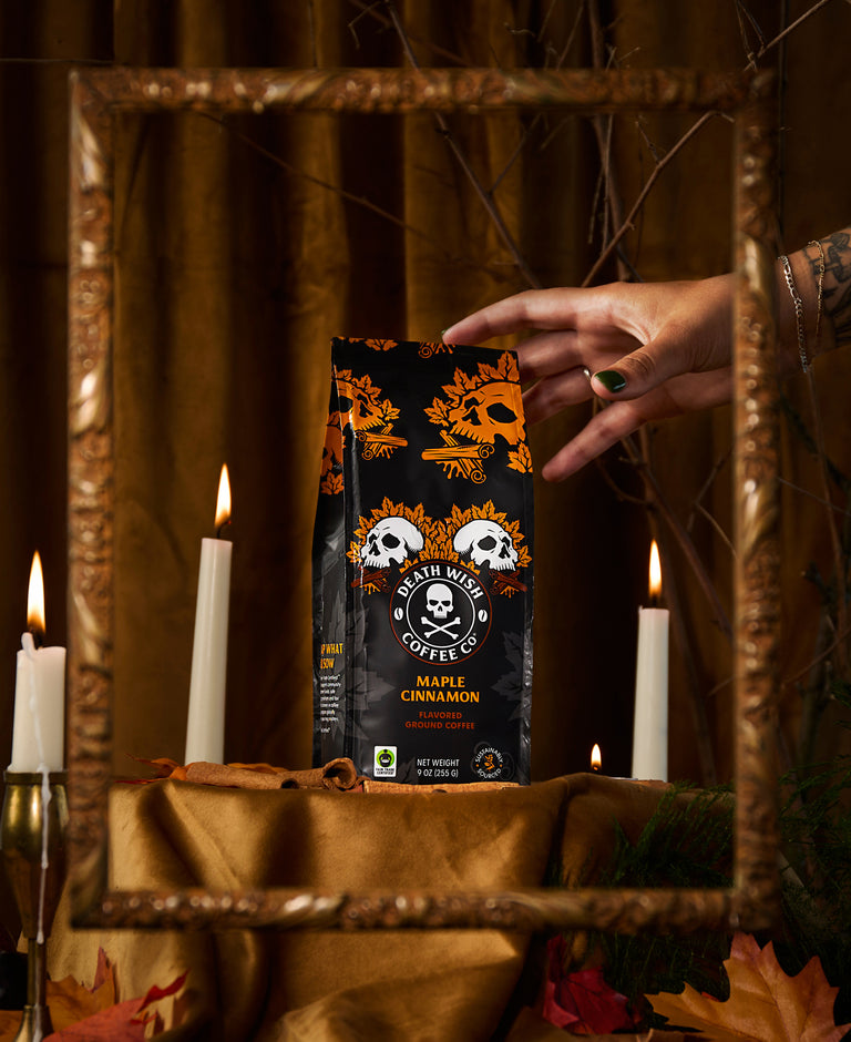 A hand reaching for Maple Cinnamon Death Wish Coffee.