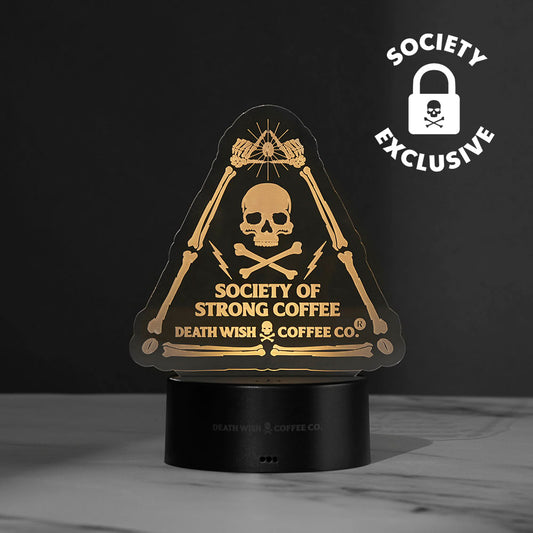 The Death Wish Coffee Neon Necromancer LED Light lit up using the Society of Strong Coffee acrylic insert.