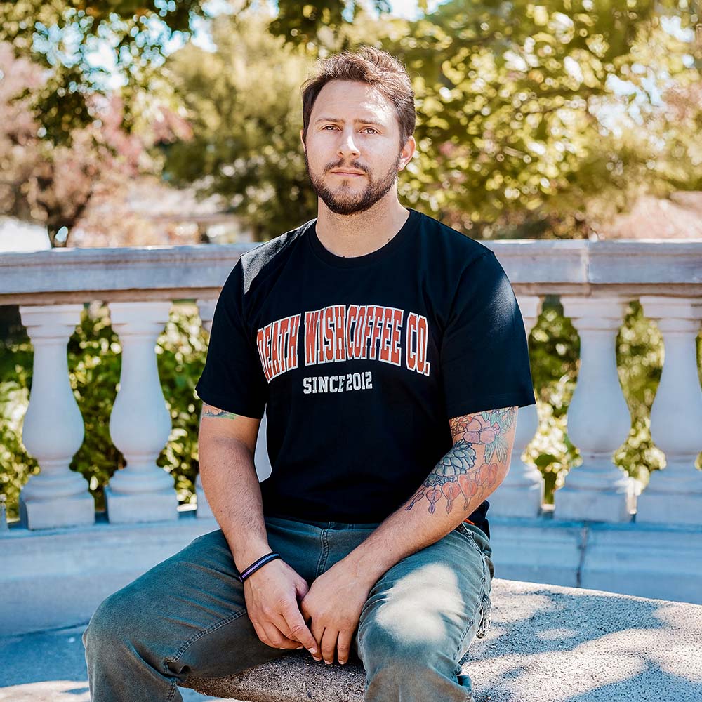 A model wearing the Death Wish Coffee Varsity Brews Tee.