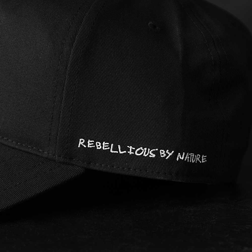 A close up of the Rebellious by Nature embroidery on the Death Wish Coffee Black Rebellious By Nature Snapback.