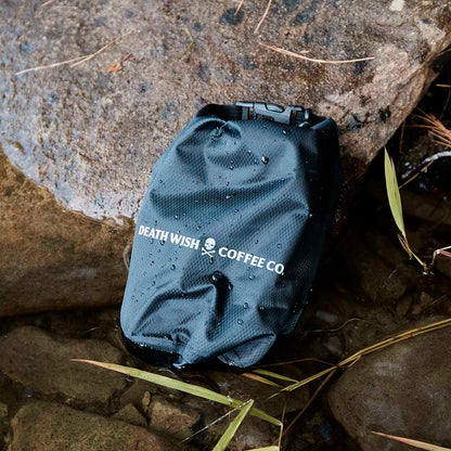 The Death Wish Coffee Rock The Boat Waterproof Bag resting on a rock.