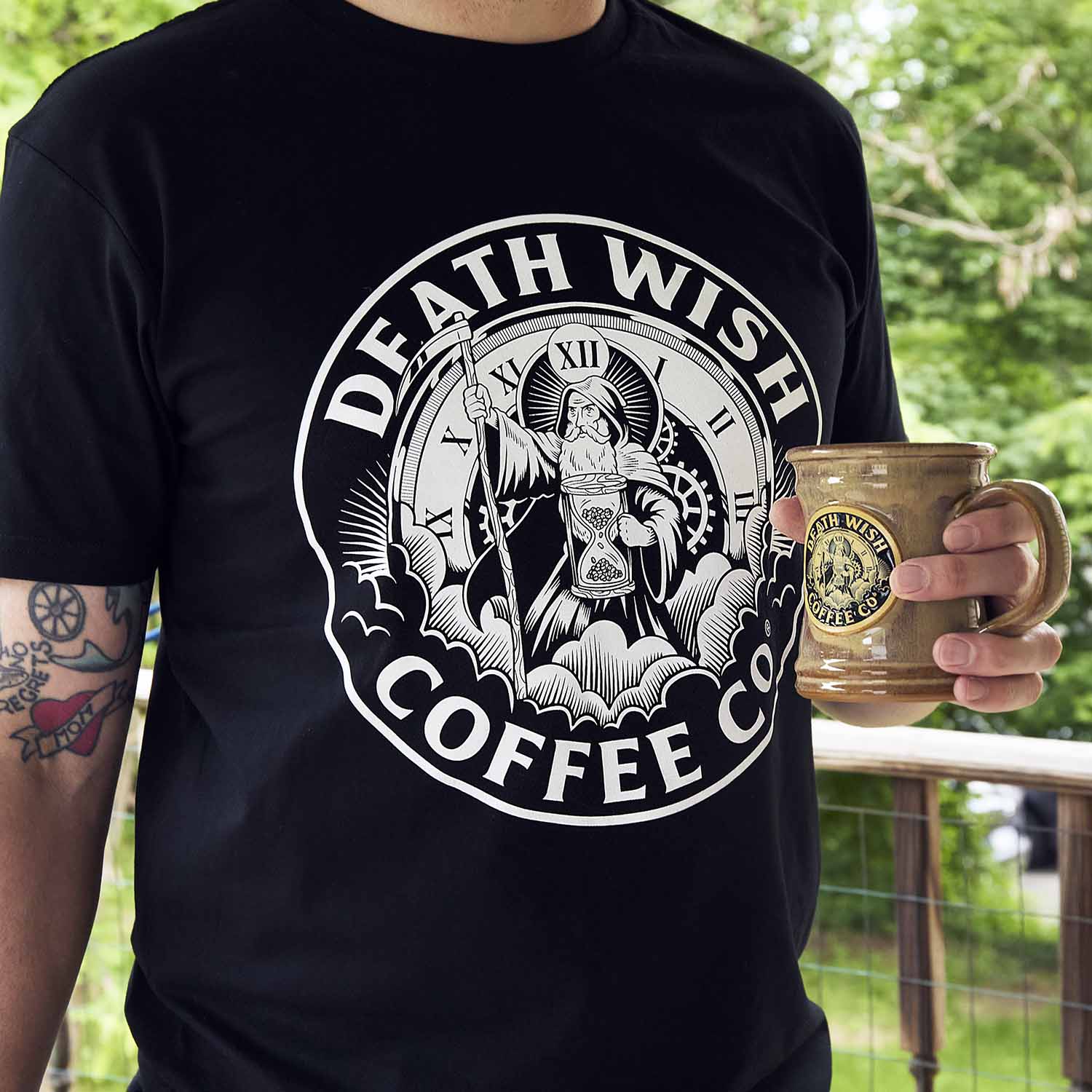 A model wearing the Death Wish Coffee Father Time Tee and using the matching Father Time Mug.