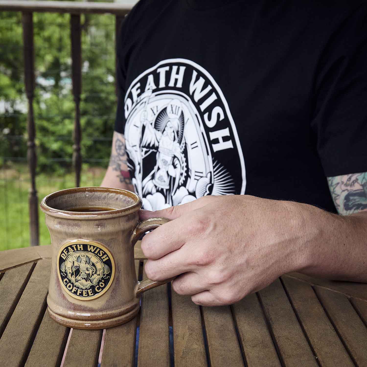 A model wearing the Death Wish Coffee Father Time Tee and using the matching Father Time Mug.
