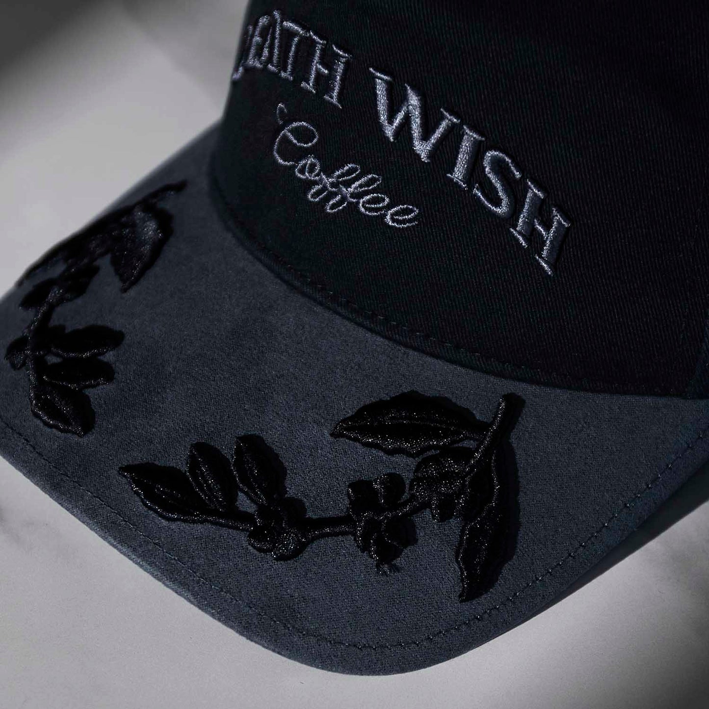 The visor embroidery detail of the Death Wish Coffee Graveyard Shift Snapback.