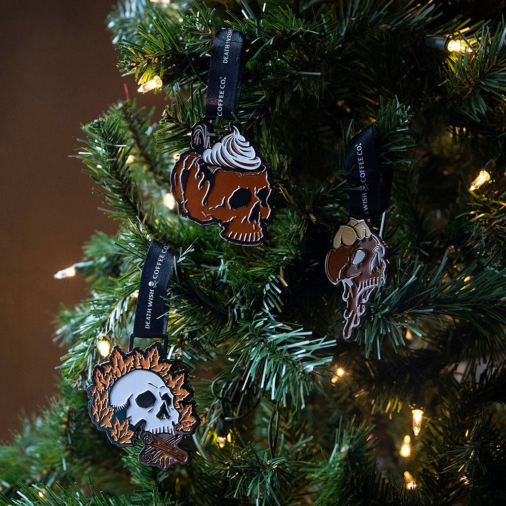 The Death Wish Coffee Deck the Skulls Ornament Set hanging in a tree.