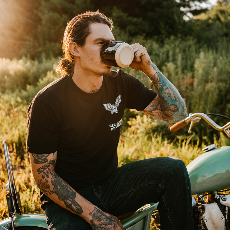 A model drinking from a Death Wish Coffee mug in a Death Wish Coffee shirt.